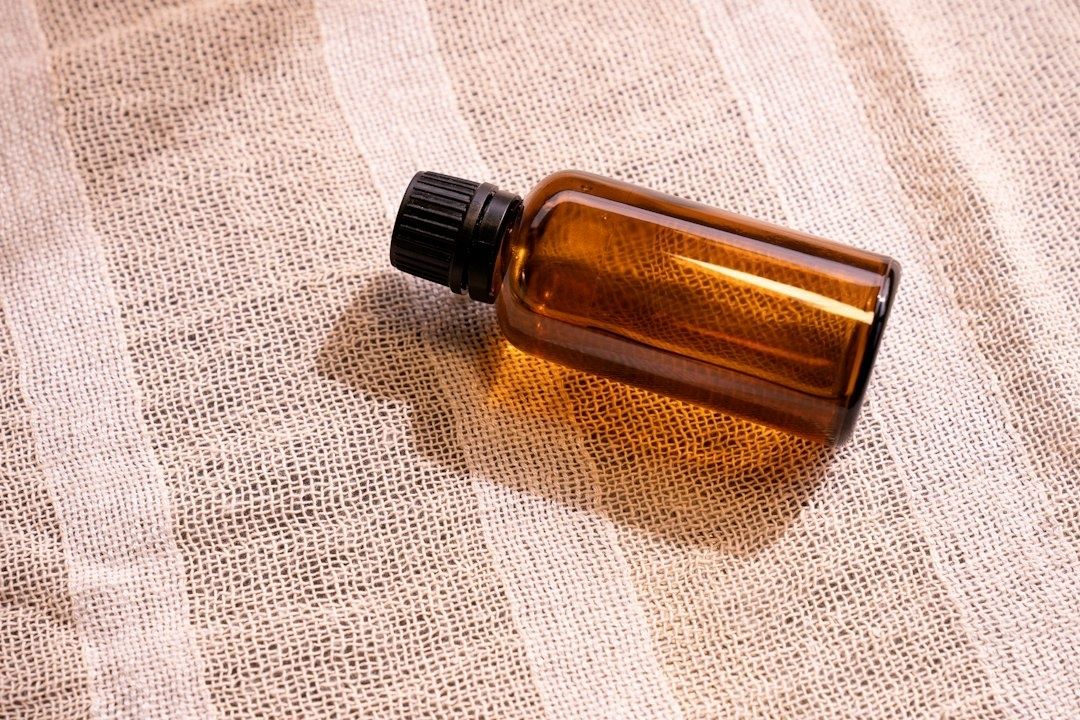 Liten brun glasflaska med svart lock på naturfärgad väv